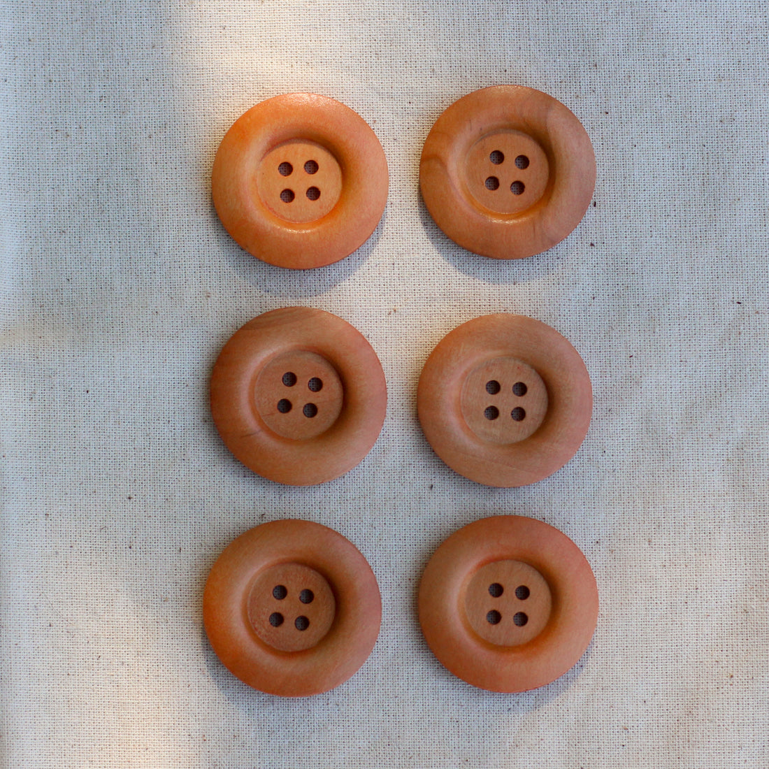 Set of 6 wooden buttons. Each button has four holes and is in a natural timber.